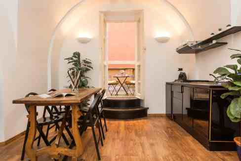 Cozy dining space with wooden table, black chairs, and balcony view in a stylish interior.