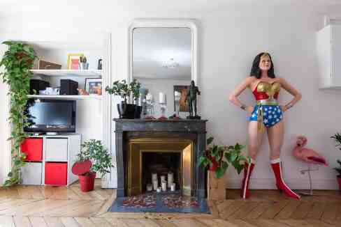 Bright living room with fireplace, plants, and a woman in Wonder Woman costume.