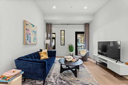 Stylish modern living room featuring a blue velvet sofa, contemporary decor, and a flat-screen TV.