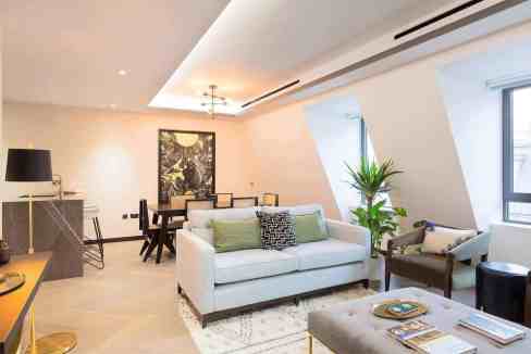 Modern living room with white sofa, large windows, and stylish decor in Soho.