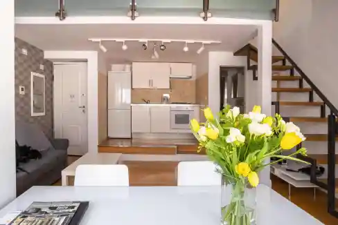 Contemporary open-plan kitchen and living area featuring sleek cabinetry, a staircase, and a vibrant.