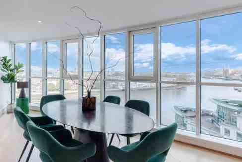 Modern dining space with panoramic river views and large windows.