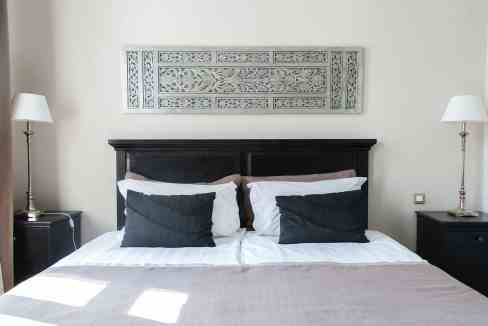 Elegant bedroom with black and white bedding, decorative wall art, and ambient lighting.