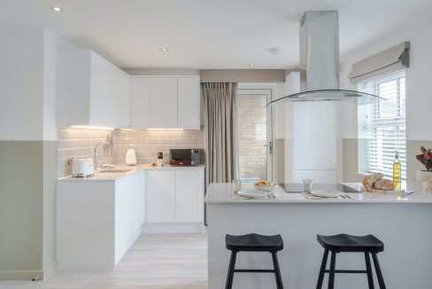 Contemporary kitchen in a serviced apartment with white cabinets and island.