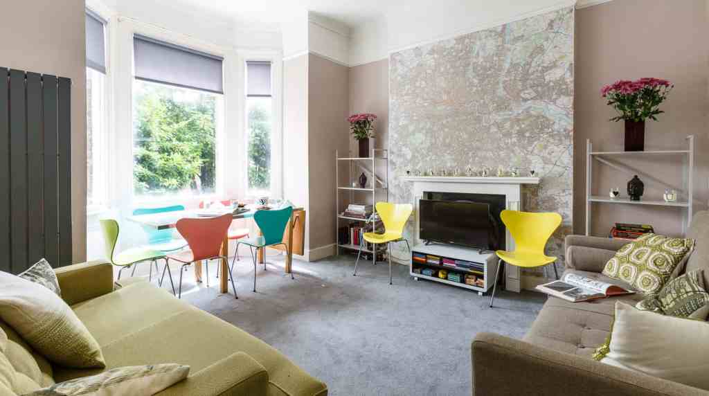 Bright living room with colorful chairs, large windows, and modern decor, ideal for relaxing and soc.