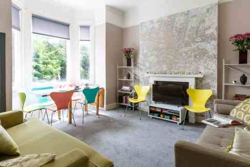 Bright living room with colorful chairs, large windows, and modern decor, ideal for relaxing and soc.