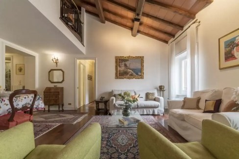 Spacious living room with high wooden ceiling, classic furniture, and natural light.