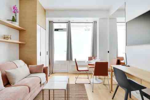 Bright and airy living room in a serviced apartment with large windows and contemporary furniture.