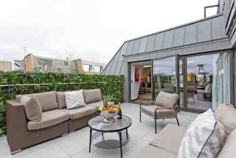 Modern rooftop terrace with outdoor seating and city views.