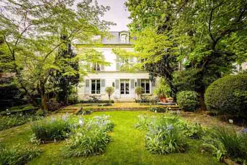 Elegant garden view of Montmartre Garden Manor with lush greenery and flowering plants.