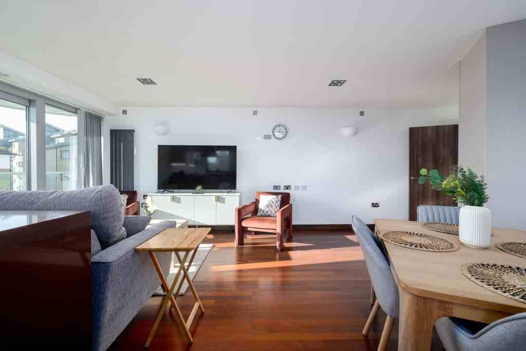 Spacious living room with wooden floors, large windows, and contemporary furniture for a cozy, styli.