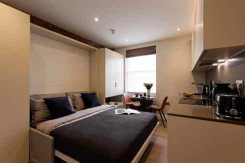 Cozy bedroom in a serviced apartment with a large bed and workspace.