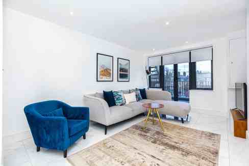 Bright modern living room with large windows, white walls, and contemporary furniture.