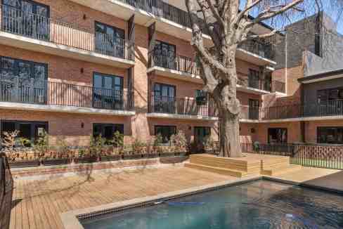 Outdoor pool and wooden deck at modern apartment complex in an urban setting.