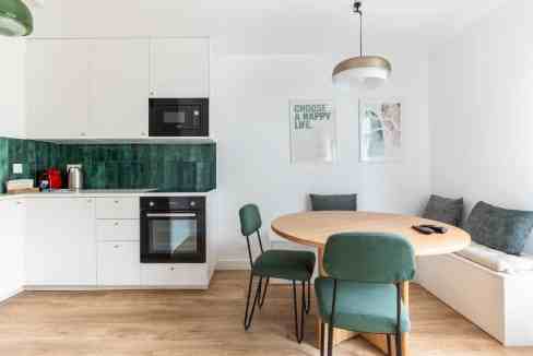 Contemporary kitchen with green backsplash and dining table in Paris apartment.