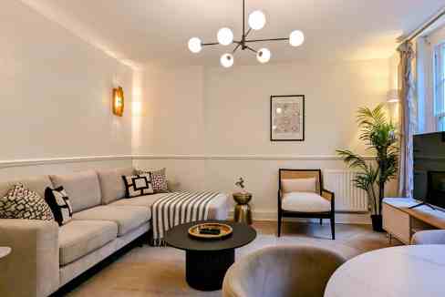 Modern living room in Chancery City Suite with sofa, armchair, and TV.