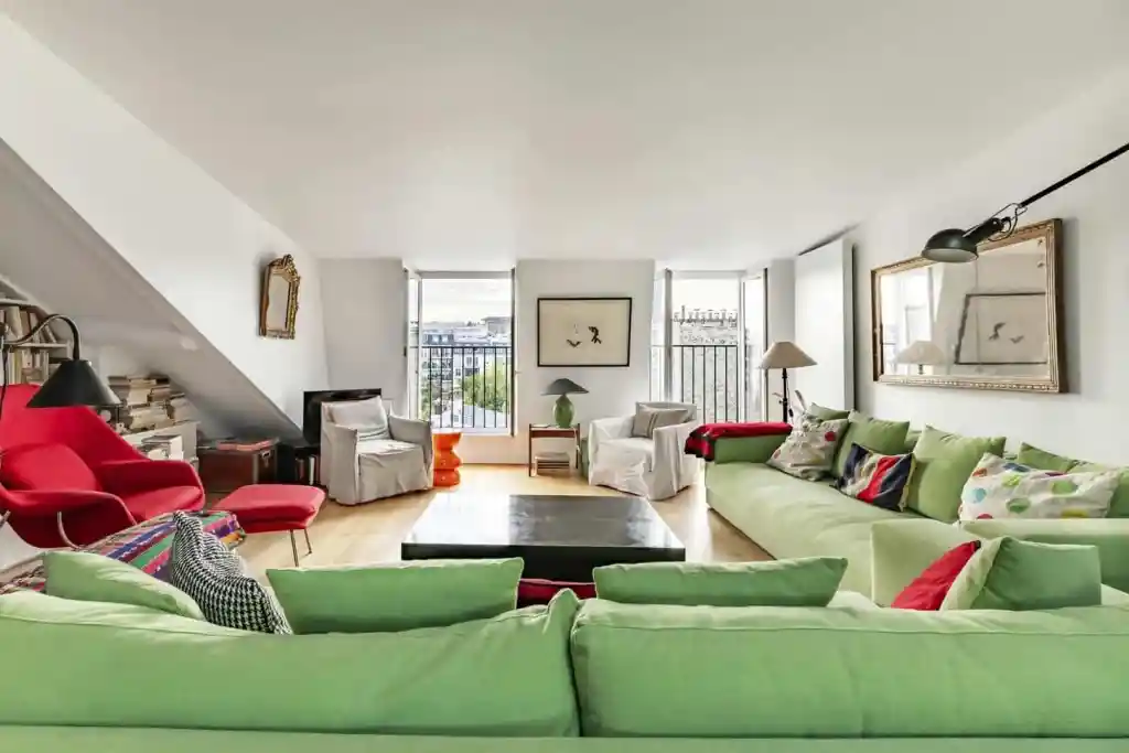 Spacious living room with colorful sofas and large windows in Montparnasse Artistry Suite.
