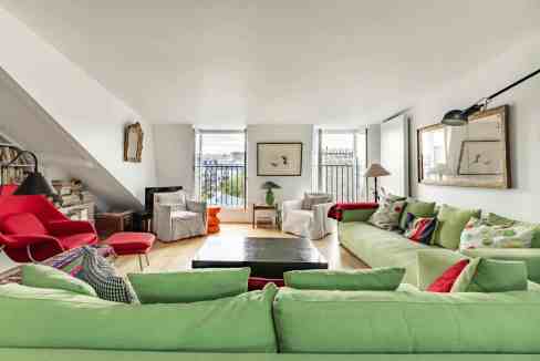 Spacious living room with colorful sofas and large windows in Montparnasse Artistry Suite.