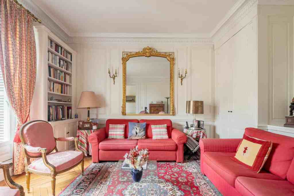 Luxurious living room with classic Haussmann decor and red upholstery.