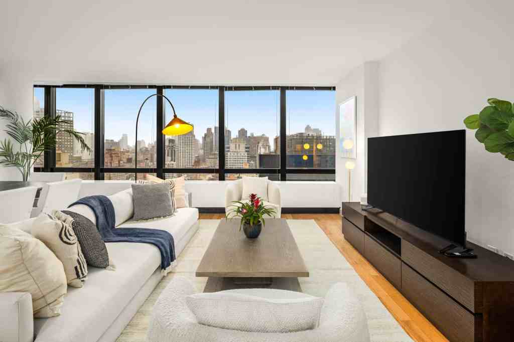 Bright living room with large windows showcasing city skyline and modern decor.