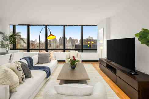 Bright living room with large windows showcasing city skyline and modern decor.
