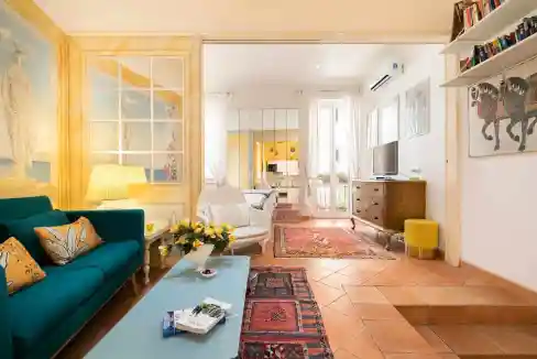 Bright living room with colorful furniture, artwork, and natural light.