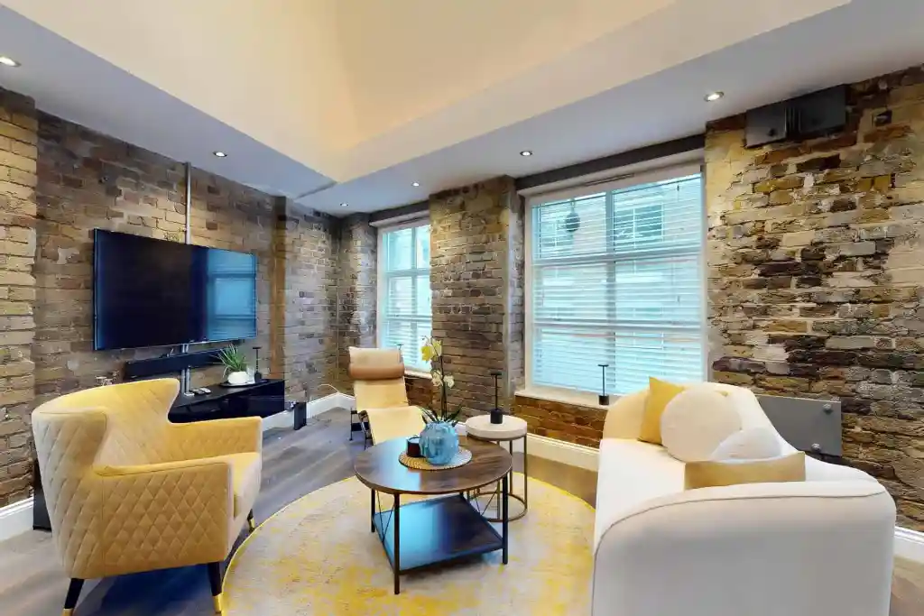 Stylish living room with exposed brick walls and large windows in Shoreditch Skyline House.