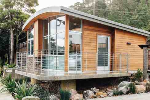 Contemporary tiny house with curved roof and large glass windows.