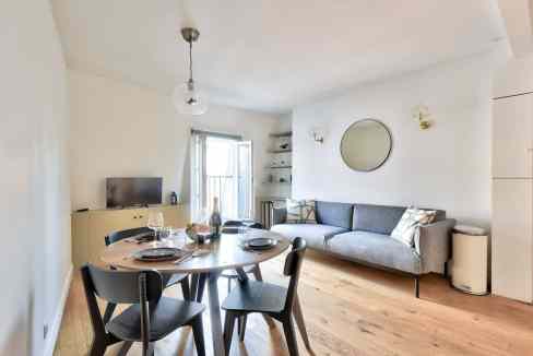 Bright living room with dining table, sofa, and minimalist decor in a contemporary apartment.