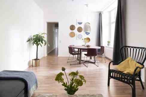 Bright minimalist living room with dining space, large window, and stylish furniture.