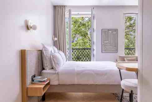 Bright, airy bedroom with large windows and minimalist decor.