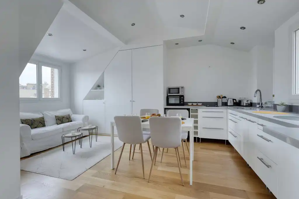 Contemporary white kitchen and cozy living space with large windows and sleek design.