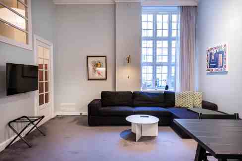 Contemporary living room with large window, black sofa, and minimalist decor.