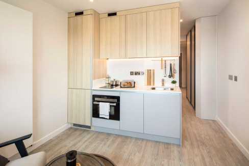 Contemporary kitchen in Croydon serviced apartment with light wood cabinets.