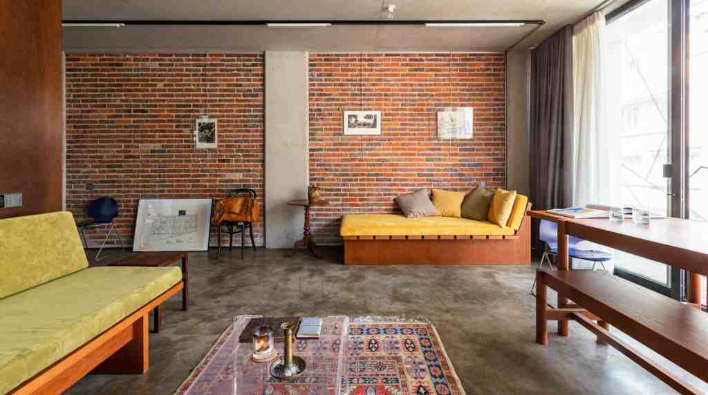 Stylish living room with brick wall, yellow sofa, and large window.