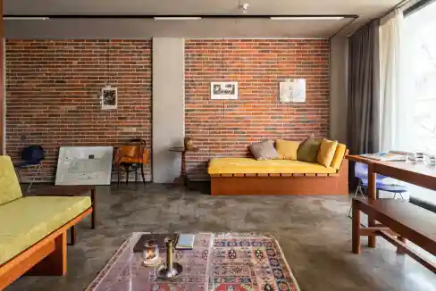 Stylish living room with brick wall, yellow sofa, and large window.