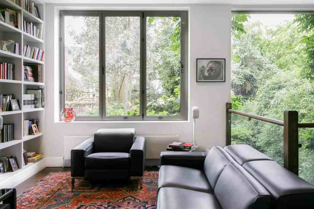 Bright living room with large windows and black leather sofas.