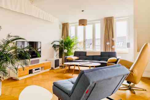 Bright living room with large windows, contemporary sofa, and wooden flooring.