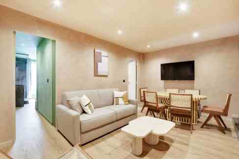 Bright living room with sofa, dining table, and wall-mounted TV in Paris.