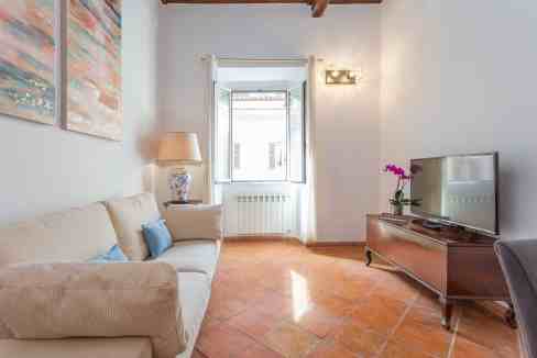 Bright living room with a large window, beige sofa, and modern decor. Perfect for relaxing and enter.
