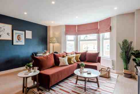 Bright living room with large windows, cozy sofa, and modern decor.