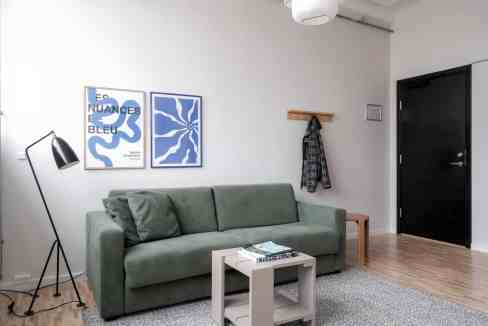 Stylish living room in a serviced apartment with green sofa and modern decor.