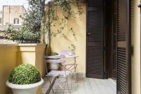 Charming balcony featuring potted greenery, a small table, and chairs, perfect for relaxing outdoors.