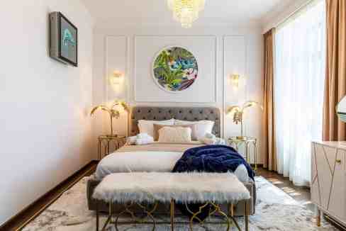 Beautiful bedroom interior featuring a plush bed, stylish lighting, and contemporary artwork for a c.