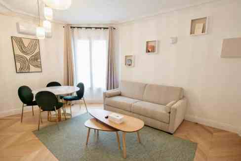 Bright and stylish living room with sofa, dining area, and decor.