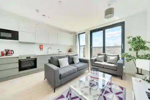 Bright living room with large windows, gray sofas, and a glass coffee table.