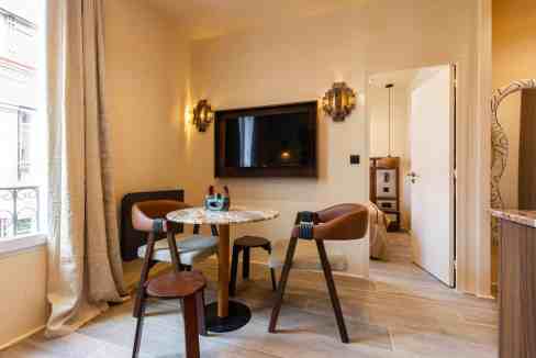 Comfortable living room with dining area, TV, and natural light in Paris apartment.