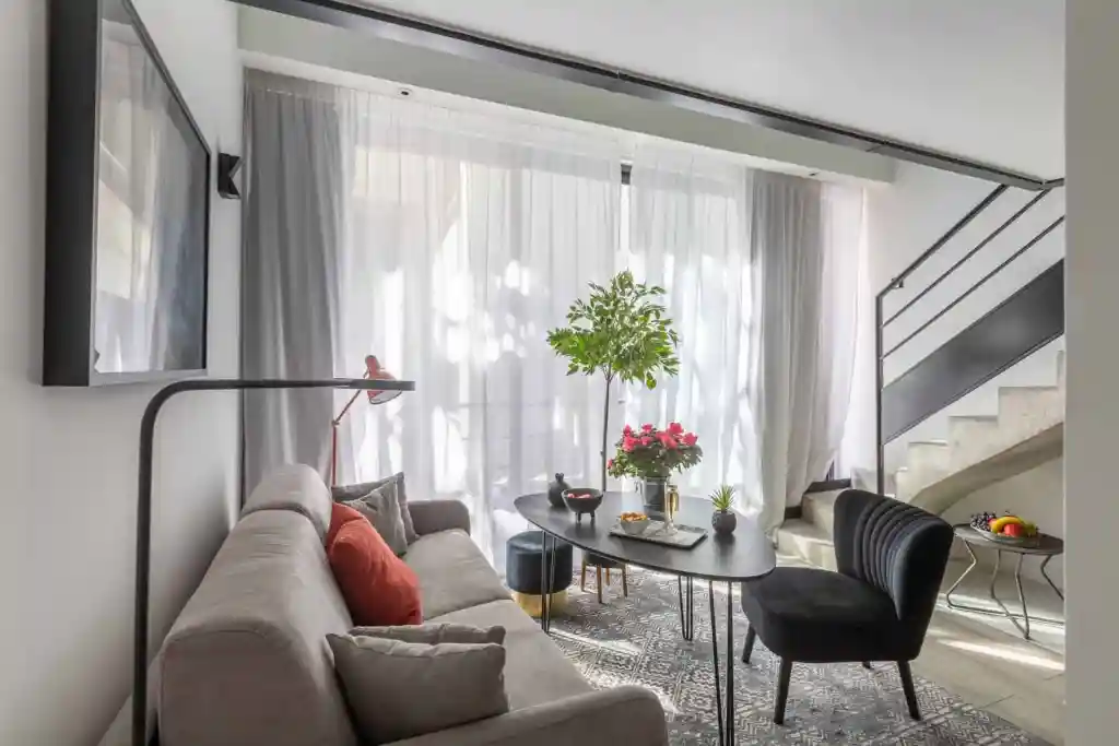 Bright living room with sofa, armchair, and large window with curtains.
