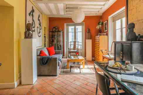 Bright living room with vibrant orange and yellow walls, eclectic furniture, and Asian-inspired art.
