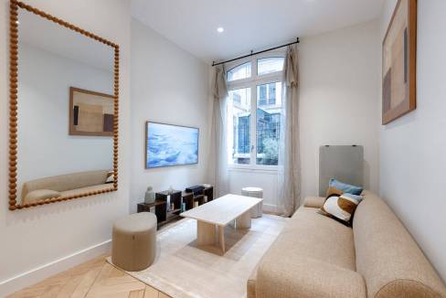 Bright living room with beige sofa, wall art, and large window with curtains.